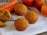 Muffin alle carote su tovaglietta bianca con carote e succo di frutta sullo sfondo