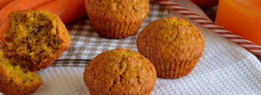 Muffin alle carote su tovaglietta bianca con carote e succo di frutta sullo sfondo