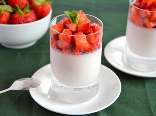 Bicchieri di panna cotta alle fragole con sopra fragole fresche