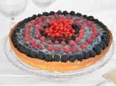 Alzatina di vetro con sopra la crostata ai frutti di bosco intera