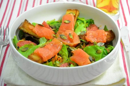 Ciotola bianca con insalata con salmone affumicato su tovaglietta