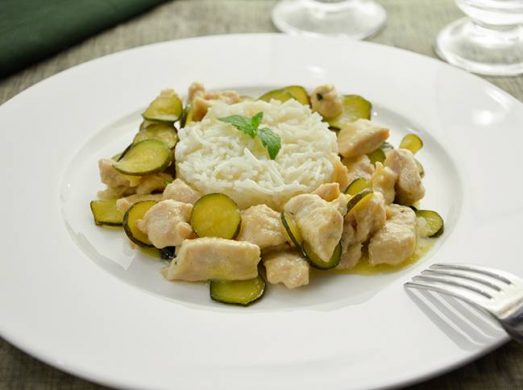 Piatto bianco con bocconcini di pollo e zucchine e riso basmati