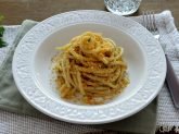 Piatto bianco con spaghetti con acchiughe e pangrattato su tavola apparecchiata