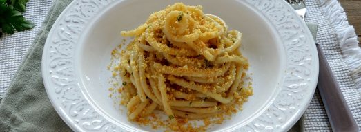 Piatto bianco con spaghetti con acchiughe e pangrattato su tavola apparecchiata