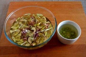 fettine e gambi di carciofi in acqua fredda con gocce di limone