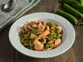 Piatto con seppie e piselli su tavola con baccelli e tovaglietta