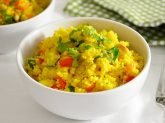 Ciotola di cous cous alle verdure saltate in primo piano con tavaglietta a quadretti verde e bianca