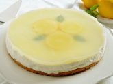 Cheesecake al limone intera su piatto bianco con limoni sullo sfondo