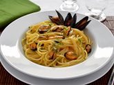 Piatto binaco con spaghetti con le cozze su tavola apparecchiata