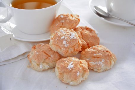 Tavola apparecchiata di bianco con biscotti al cocco in primo piano