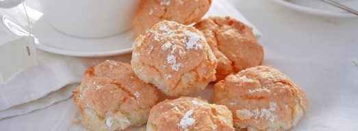 Tavola apparecchiata di bianco con biscotti al cocco in primo piano