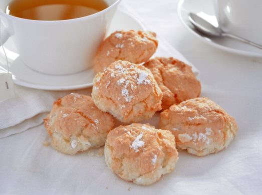 Tavola apparecchiata di bianco con biscotti al cocco in primo piano
