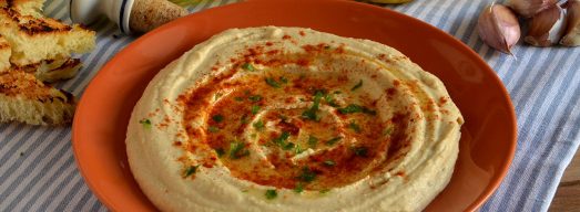 Piatto arancione con hummus su tovaglietta a quadretti