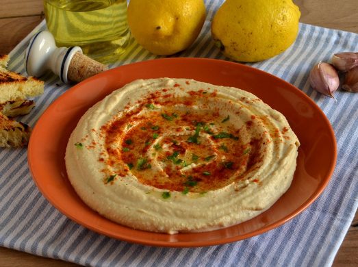 Piatto arancione con hummus su tovaglietta a quadretti