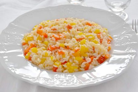 Piatto bianco con risotto ai peperoni su tovaglia bianca