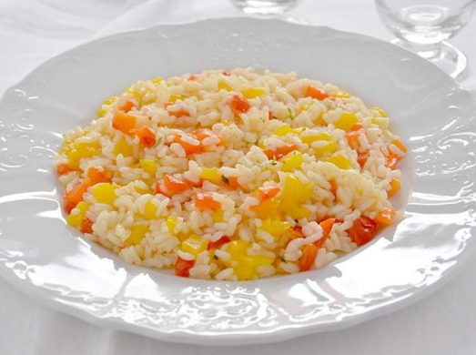 Piatto bianco con risotto ai peperoni su tovaglia bianca