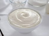 Ciotola bianca con crema al latte su tavola bianca