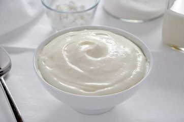 Ciotola bianca con crema al latte su tavola bianca