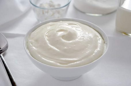 Ciotola bianca con crema al latte su tavola bianca