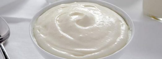 Ciotola bianca con crema al latte su tavola bianca