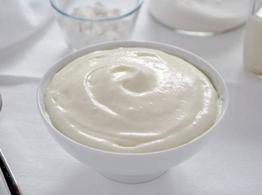 Ciotola bianca con crema al latte su tavola bianca