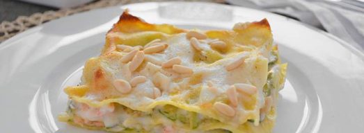 Piatto bianco con porzione di lasagna e tavola apparecchiata.