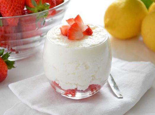 Bicchiere di mousse al limone con fragole fresche con limoni e fragole sullo sfondo