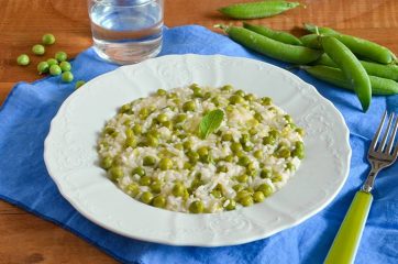 Piatto di risotto con i piselli su tovaglietta azzurra e baccelli sullo sfondo