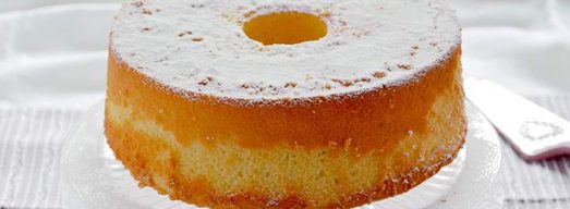 Torta con zucchero a velo su alzatina e tovaglia bianca