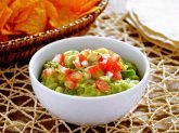 Ciotola bianca con Guacamole con nachos sullo sfondo