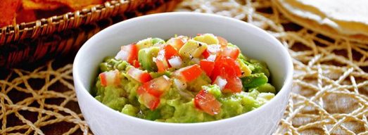 Ciotola bianca con Guacamole con nachos sullo sfondo