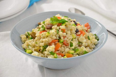 Ciotola celeste con verdura e feta su tavola bianca