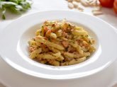 Piatto con pasta con pesto alla trapanese su tavola apparecchiata