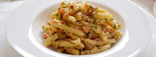 Piatto con pasta con pesto alla trapanese su tavola apparecchiata