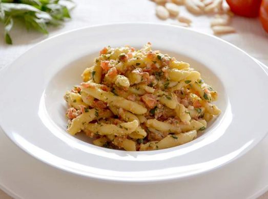 Piatto con pasta con pesto alla trapanese su tavola apparecchiata