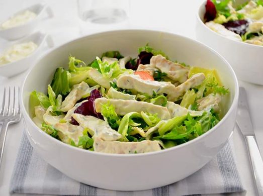 Ciotola bassa con insalata di pollo su tavaglietta a righe