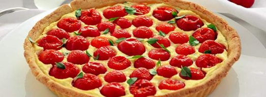 Piatto da portata con torta salata ricotta e pomodorini su tovaglia bianca