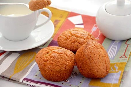 Tre muffin su tovaglietta e latte e zucchero sullo sfondo