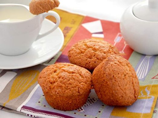 Tre muffin su tovaglietta e latte e zucchero sullo sfondo