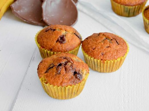 Tre muffins in primo piano e altri con pezzi di cioccolato e banane sullo sfondo