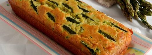 Plumcake intero su piatto rettangolare con asparagi freschi sullo sfondo