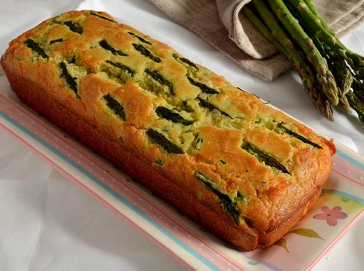 Plumcake intero su piatto rettangolare con asparagi freschi sullo sfondo