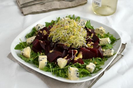 Piatto piano con insalata di barbabietole su tavola apparecchiata