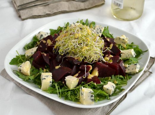 Piatto piano con insalata di barbabietole su tavola apparecchiata