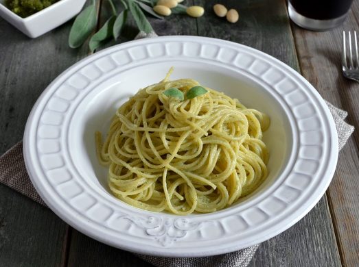 Piatto di spaghetti con pesto di salvia con salvia e pesto sullo sfondo