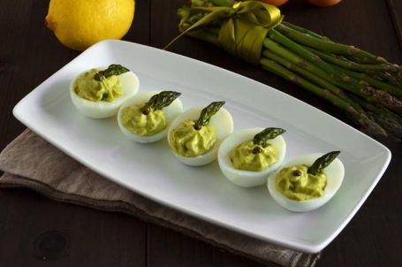 Piatto con uova divise a metà e farcite e asparagi freschi sul tavolo