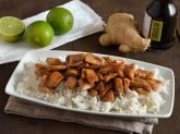 Piatto con pollo alla salsa di soia su riso basmati con lime, zenzero e soia sullo sfondo