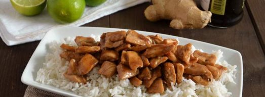 Piatto con pollo alla salsa di soia su riso basmati con lime, zenzero e soia sullo sfondo