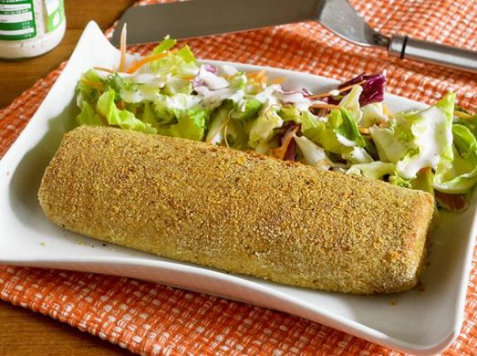 Polpettone di tonno e patate su piatto bianco con contorno di insalata