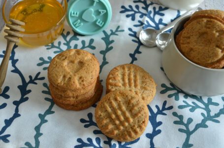 Biscotti su tovaglietta con vasetto di miele e latte